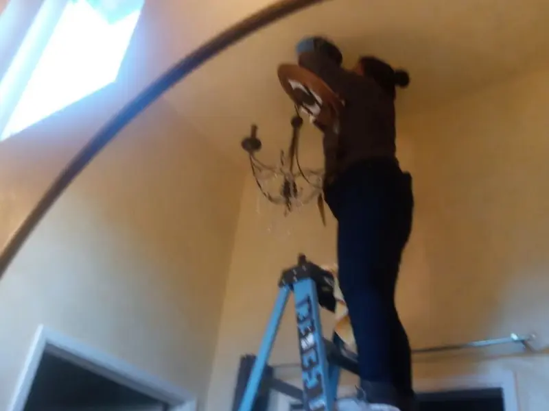 Electrician installing a chandelier in a Madison Heights residence
